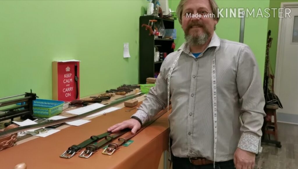 Mark at the bench smiling with 3 finished belts